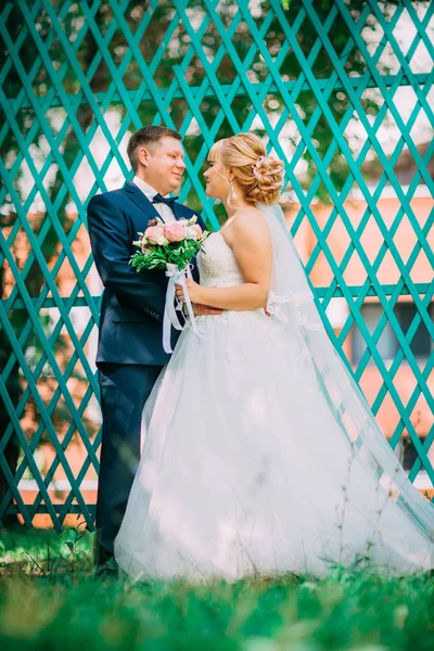 Mariée et marié sur le fond de la clôture de jardin — Photo