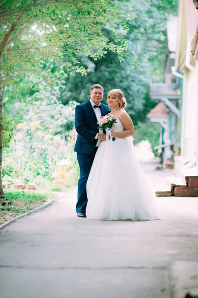 Bruden och brudgummen på bakgrunden av trädgårdsstaketet — Stockfoto