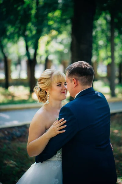 Par bruden och brudgummen på bakgrunden av parkens träd — Stockfoto