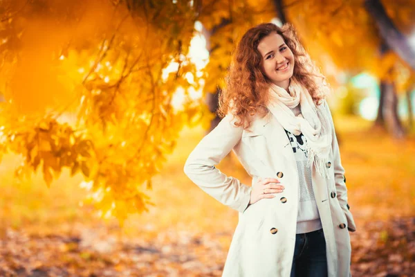 Молодая девушка в легком пальто на фоне осеннего парка — стоковое фото