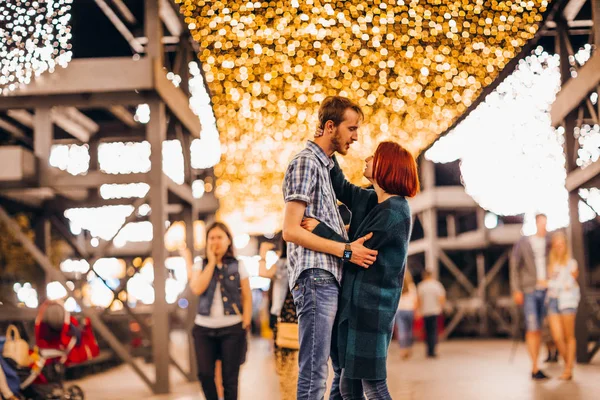 Gelukkige paar omarmen in de avond op een lichte slingers — Stockfoto