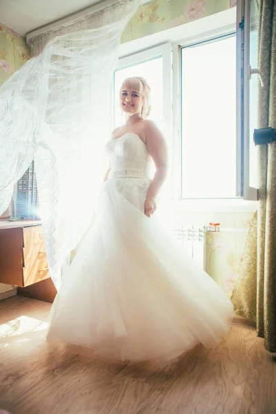 Retrato de jovem bela noiva feliz em pé perto de uma janela — Fotografia de Stock