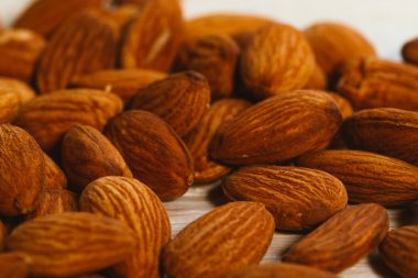 Beyaz ahşap arka planda bir avuç badem.