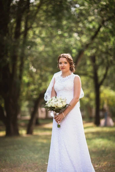 Genç gelin düğün buket üzerinde park backgro ile portresi — Stok fotoğraf