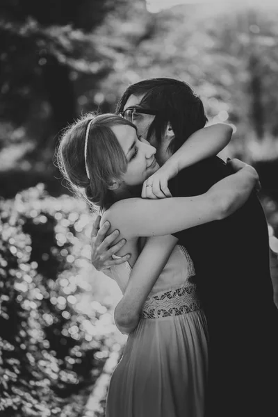 Black and white photo of guy the girl embracing on a background park alley — Stock Photo, Image