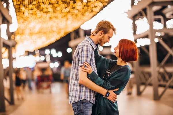 Pareja feliz abrazándose en la noche en una guirnalda de luz — Foto de Stock