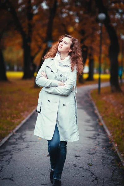 Young girl in a light coat on the background of autumn park — Stock Photo, Image