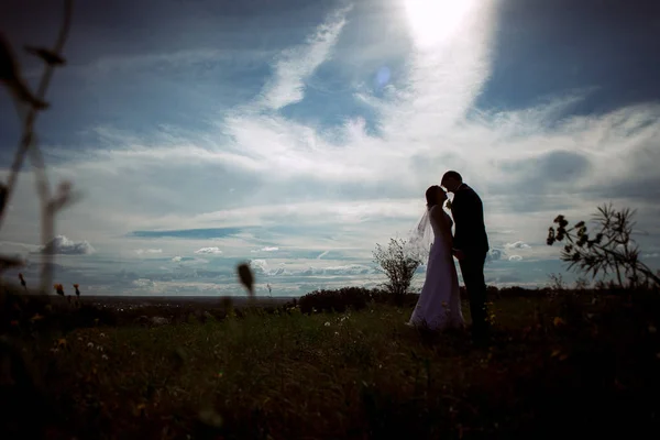 Silhouetten von Braut und Bräutigam am Feldhimmel im Hintergrund — Stockfoto