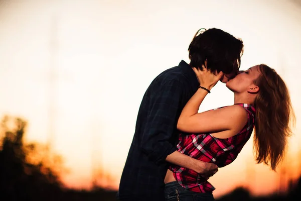 Ragazzo e la ragazza sono in piedi baci in il tramonto sfondo — Foto Stock