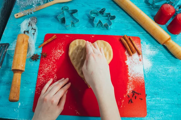 Дівчина закочує тісто на червоній дошці до синього дерев'яного столу — стокове фото