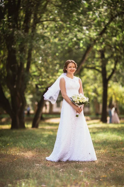 Ritratto di una giovane sposa con bouquet da sposa sul retro del parco — Foto Stock