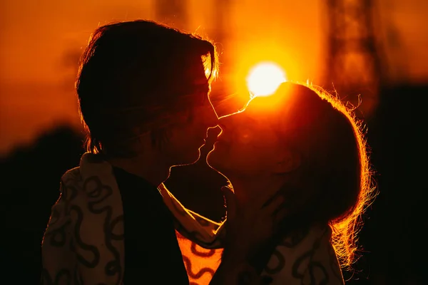 Cara e a menina estão de pé contra o pôr do sol em uma planície — Fotografia de Stock