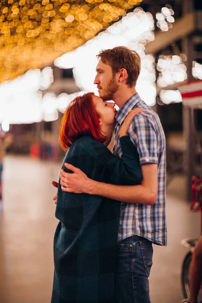 Pasangan bahagia merangkul dan mencium di malam hari pada karangan bunga cahaya — Stok Foto
