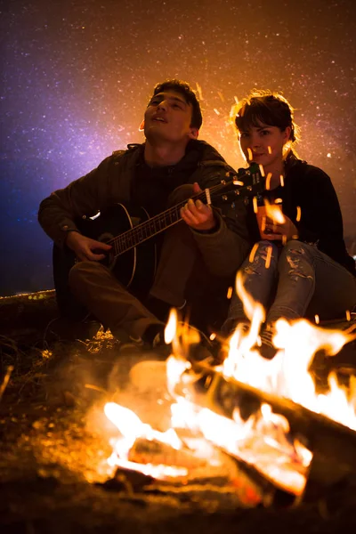 Homme joue de la guitare et de la femme sur le feu sur le fond du ciel étoilé — Photo