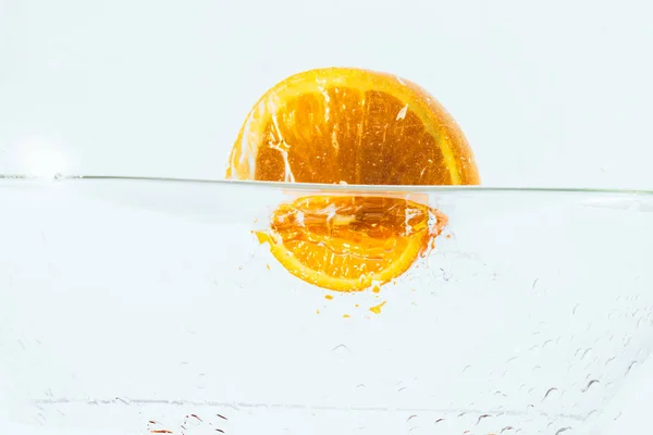 Moitiés orange tombant dans l'eau sur fond blanc — Photo
