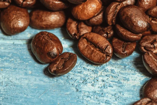 Dark many roasted coffee beans on blue background — Stock Photo, Image