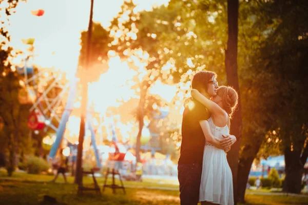 Killen och tjejen kramar på nöjesparken bakgrund — Stockfoto