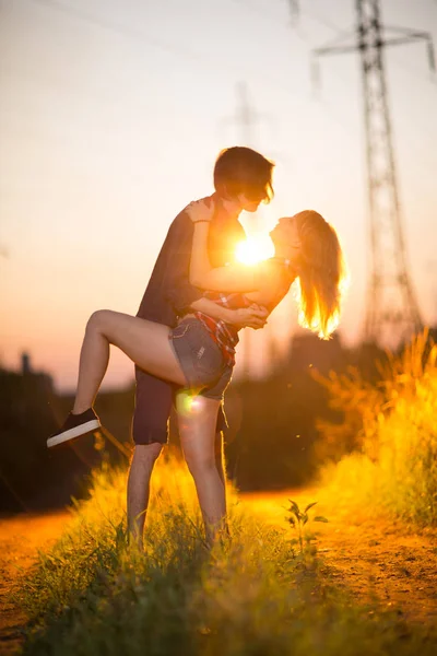 Chico y la chica están de pie besándose en el fondo del atardecer —  Fotos de Stock