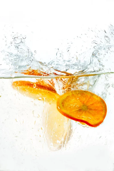 Orange halves falling into water on white background — Stock Photo, Image