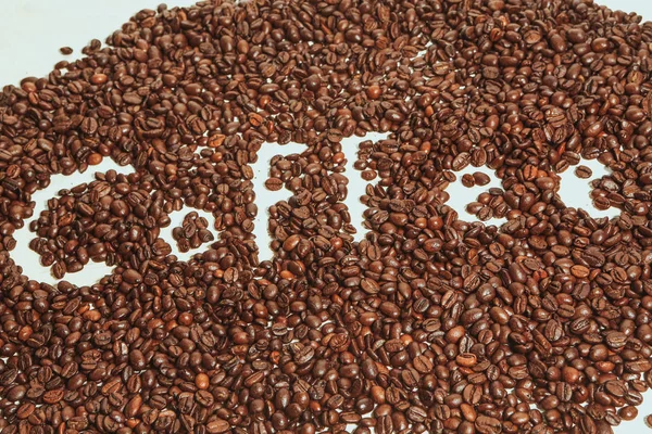 The words coffee written against scattered natural coffee — Stock Photo, Image