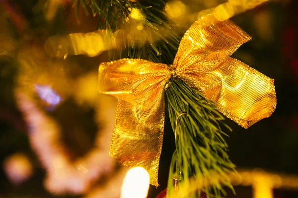 Golden bow on a background of green Christmas tree branches — Stock Photo, Image