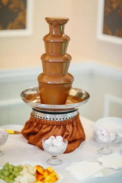 Chocolate fountain stands at the wedding banquet table Stock Picture