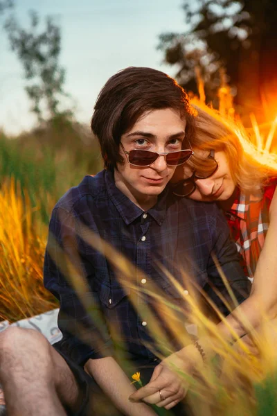 Парень и девушка, сидящие в траве на фоне заката — стоковое фото