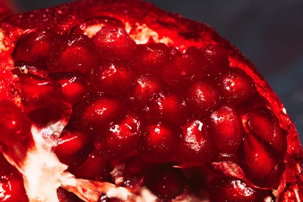 Red sliced pomegranate on a blue abstraction background close up — Stock Photo, Image