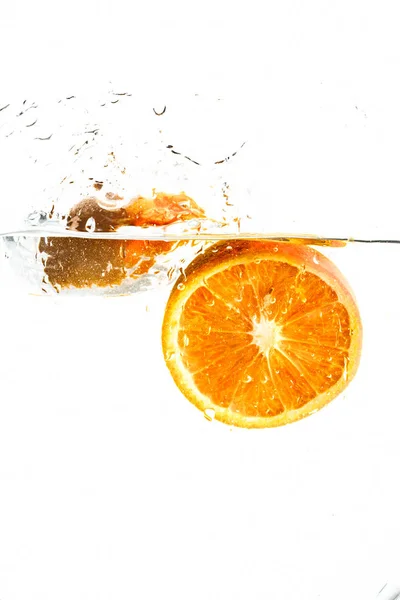 Orange halvor faller i vatten på vit bakgrund — Stockfoto