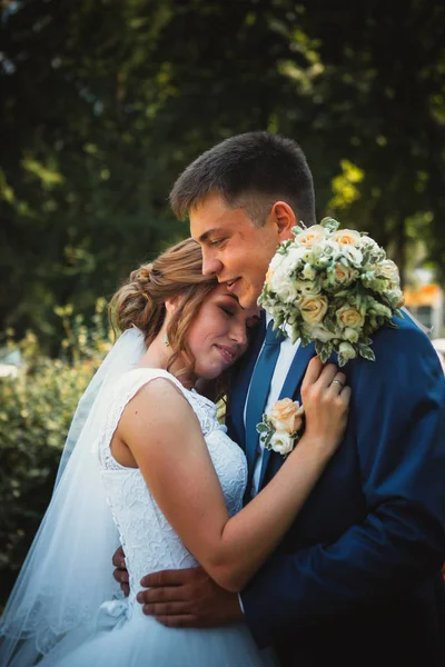 Casal noivo e noiva abraçando e beijando no parque da natureza fundo — Fotografia de Stock