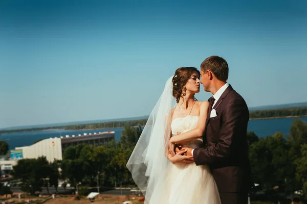 Unga bruden och brudgummen paret på den himmel bakgrunden — Stockfoto