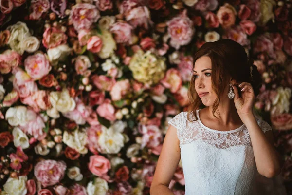 Bela noiva no fundo de uma parede de flores — Fotografia de Stock