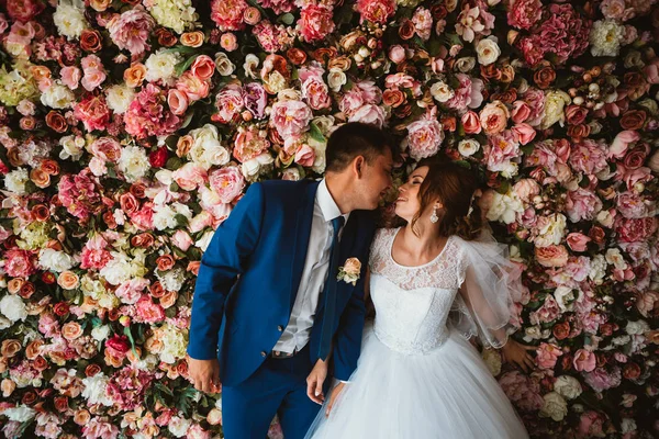 Bir çiçek duvarının arkasında güzel bir gelin ve damat.