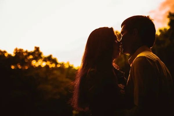 Bela jovem casal no fundo do pôr do sol — Fotografia de Stock