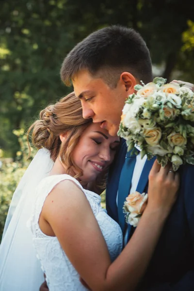 Couple marié et mariée embrasser et embrasser sur le fond du parc naturel — Photo