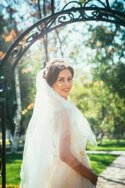 Genç, güzel bir gelin parktaki bir çardakta duruyor..