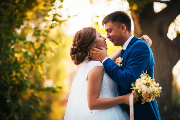 Paar bruidegom en bruid knuffelen en kussen op natuur park achtergrond — Stockfoto