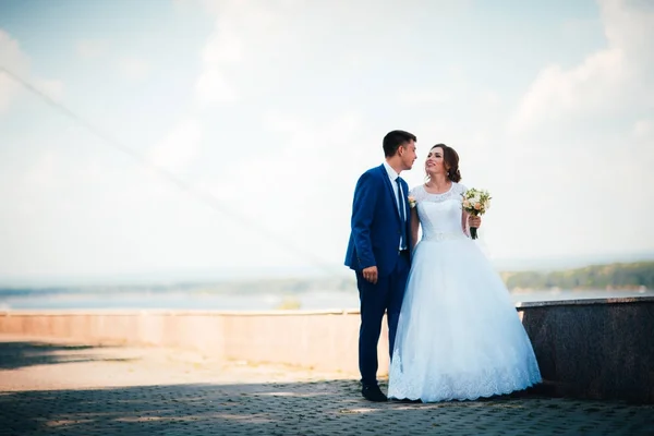 De bruid en bruidegom staan op de achtergrond van de rivier. — Stockfoto