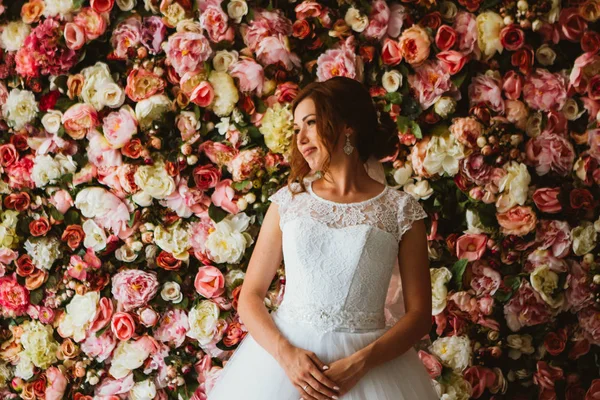 Krásná nevěsta na pozadí stěny květin — Stock fotografie