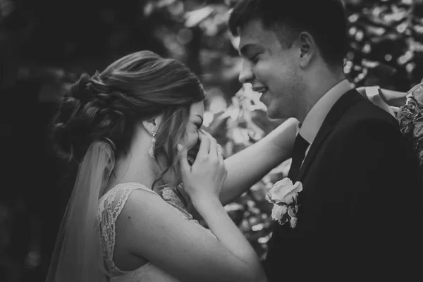 Zwart-wit foto paar bruidegom en bruid op de achtergrond bladeren — Stockfoto