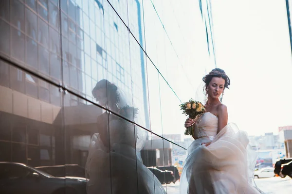 Bruden och bukett på bakrund spegel byggnader. — Stockfoto