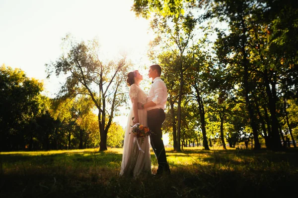 Los novios en el fondo de los árboles del parque — Foto de Stock