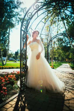 Genç, güzel bir gelin parktaki bir çardakta duruyor..