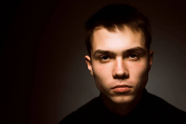 Jovem cara em um escuro estúdio fundo — Fotografia de Stock