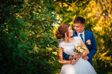 Gelin ve damat, portakal yapraklarının arka planına karşı.