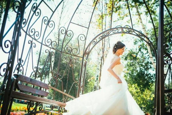 Giovane bella sposa in piedi in un gazebo del parco . — Foto Stock