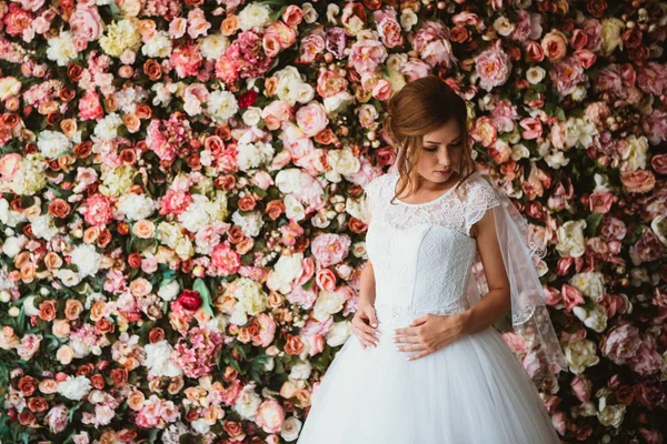 Bela noiva no fundo de uma parede de flores — Fotografia de Stock