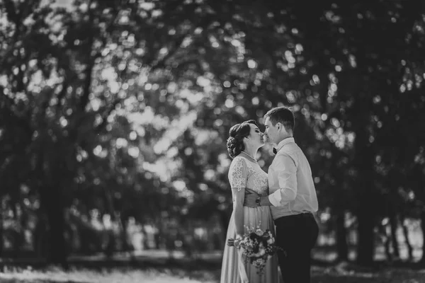 Nevěsta a ženich v pozadí stromů parku — Stock fotografie