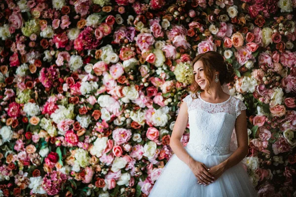 Hermosa novia en el fondo de una pared de flores — Foto de Stock