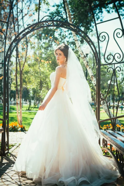 Pengantin muda yang cantik berdiri di sebuah gazebo taman. — Stok Foto